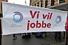 Bildet viser en fane under 1. mai-markering. På fanen står det «Vi vil jobbe».