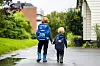 Bildet viser to små gutter med ryggen til, på vei til skole og barnehage. De holder hender.