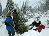 Bildet viser en mann, en kvinne og tre barn som er ute i skogen og hugger juletre.