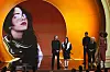 Billie Eilish og Finneas tar imot Grammy-pris på en opplyst scene med stort skjermbilde av Eilish bak.
