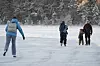 Personer på skøyter på frossen innsjø ved Sognsvann en kald vinterdag.
