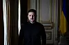 Volodymyr Zelensky står i et rom med Ukrainas flagg bak seg.