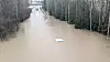 Oversvømt skogsvei ved Knapstad med en nesten sunket bil i midten av vannet