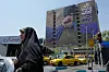 Bildet er tatt i en gate i Iran. På veggen henger en plakat med en hånd som holder på Hormuzstredet. Foto: Vahid Salemi / AP Photo / NTB