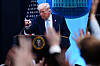 Donald Trump ved talerstol i Det hvite hus peker mot journalister med hendene hevet.