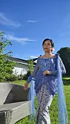 Bildet viser en kvinne fra Indonesia som står i hagen sin i Norge.