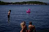 Folk bader ved Sørenga i Oslo mens en rosa badeflamingo flyter i fjorden.