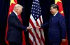 Donald Trump og Xi Jinping håndhilser foran amerikanske og kinesiske flagg på en scene.