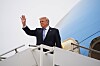 Donald Trump står i trappen til et fly og vinker ved en flyplass.