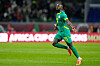 En fotballspiller i grønn Senegal-drakt løper og feirer på banen.