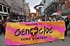 Demonstranter holder et stort rosa og oransje protestbanner i en gate i Malmö. På banneren står det «Velkommen til folkemord song contest».