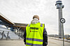 Streikevakt i gul vest står utenfor Oslo lufthavn Gardermoen med flytårn i bakgrunnen.