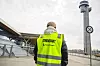 Streikevakt i gul vest står utenfor Oslo lufthavn Gardermoen med flytårn i bakgrunnen.