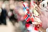 Mennesker på Slottsplassen i Oslo vifter med norske flagg under 17. mai-feiringen.