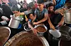 Folk får mat fra store kjeler ved et veldedig kjøkken i Nuseirat i Gaza.