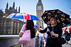 Bildet viser turister med paraply i solrike London. Foto: James Manning / AP / NTB
