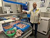 En mann står ved en fiskedisk med blå kasser fylt med sjømat i en butikk.