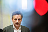 Arild Hermstad står foran en mørk bakgrunn med kraftig lys og røde detaljer under en pressekonferanse.
