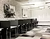 Et lyst teorilokale med en rekke datamaskiner, stoler og store vinduer langs veggen.