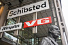 Schibsted-skilt på en moderne bygning i Oslo, med VG-skilt og en byste i forgrunnen.