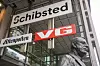 Schibsted-skilt på en moderne bygning i Oslo, med VG-skilt og en byste i forgrunnen.