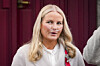 Kronprinsesse Mette-Marit står foran røde gardiner med pustemaskin på nesen.