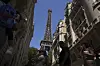 Bildet viser turister som går forbi Eiffeltårnet i Paris i Frankrike. Christophe Ena / AP / NTB