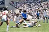 Maradona dribler med ballen mens tre engelske spillere forsøker å stoppe ham på en fotballbane full av publikum.