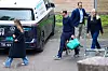 Kronprinsfamilien går på en parkeringsplass ved et sykehus, med en ambulanse og en grønn bag i forgrunnen.
