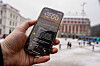 En hånd holder en mobiltelefon med nødvarsel-test på skjermen foran en byplass.