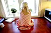 Lyshåret barn sitter bøyd med armer og bein i kors og med ryggen til på kjøkkenbenken foran et vindu