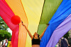 En person står under og løfter opp et regnbueflagg i en Pride-parade i Romania.
