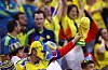 Colombia-supporter i superheltkostyme holder en kopi av VM-trofeet og jubler på tribunen.