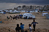 Bildet viser Gaza og barn som leker i framgrunnen. Foto: Abdel Kareem Hana / AP / NTB