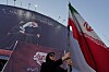 Bildet viser Ayatollah Ali Khamenei på en plakat. I framgrunnen står en kvinne. Foto: Vahid Salemi / AP / NTB