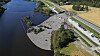 Dronebilde av et stort ras ved vannet, med jordmasser over vei, jernbane og skog.