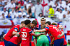 Norske fotballspillere i røde drakter og keeper i grønt samles i en sirkel på banen.