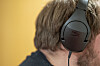 Nærbilde av en mann med svart headset mot gul bakgrunn.