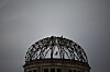 Ruinen av Atombombekuppelen i Hiroshima mot en grå himmel, med en fugl over bygningen.