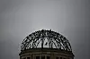 Ruinen av Atombombekuppelen i Hiroshima mot en grå himmel, med en fugl over bygningen.