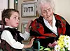 Gutt gir blomster til Jeanne Calment i et pleiehjem, med en bukett på bordet i forgrunnen.
