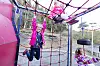 Barn leker i et rødt og blått klatrestativ ved en skoleplass.