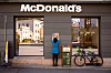 McDonald's-restaurant med logo over inngangen, en person ved veggen og en sykkel parkert utenfor.