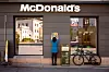 McDonald's-restaurant med logo over inngangen, en person ved veggen og en sykkel parkert utenfor.