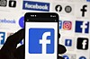 Mobiltelefon med Facebook-logo foran bakgrunn med Meta-appikoner.