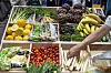 Utstilt frukt og grønnsaker i kasser, med bananer, tomater, sitroner, agurk og rotgrønnsaker.