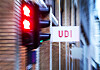 UDI-skilt på vegg ved en bygning, med røde lys og uskarpt bymiljø i bakgrunnen.