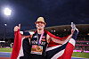 Karsten Warholm står på banen og feirer med norsk flagg etter gull på 400 meter hekk i Birmingham.