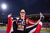 Karsten Warholm står på banen og feirer med norsk flagg etter gull på 400 meter hekk i Birmingham.