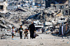 Bildet viser palestinere som går forbi ruiner på Gaza. Foto: Mahmoud Issa / Reuters / NTB